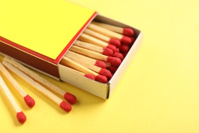 Photo of Matches in box on yellow background, closeup