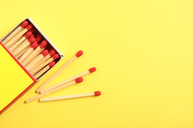 Photo of Matches and box on yellow background, flat lay. Space for text