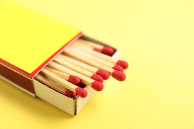 Photo of Matches in box on yellow background, closeup