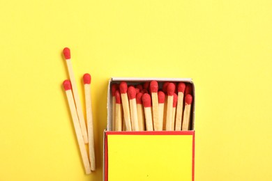 Photo of Matches and box on yellow background, flat lay. Mockup for design