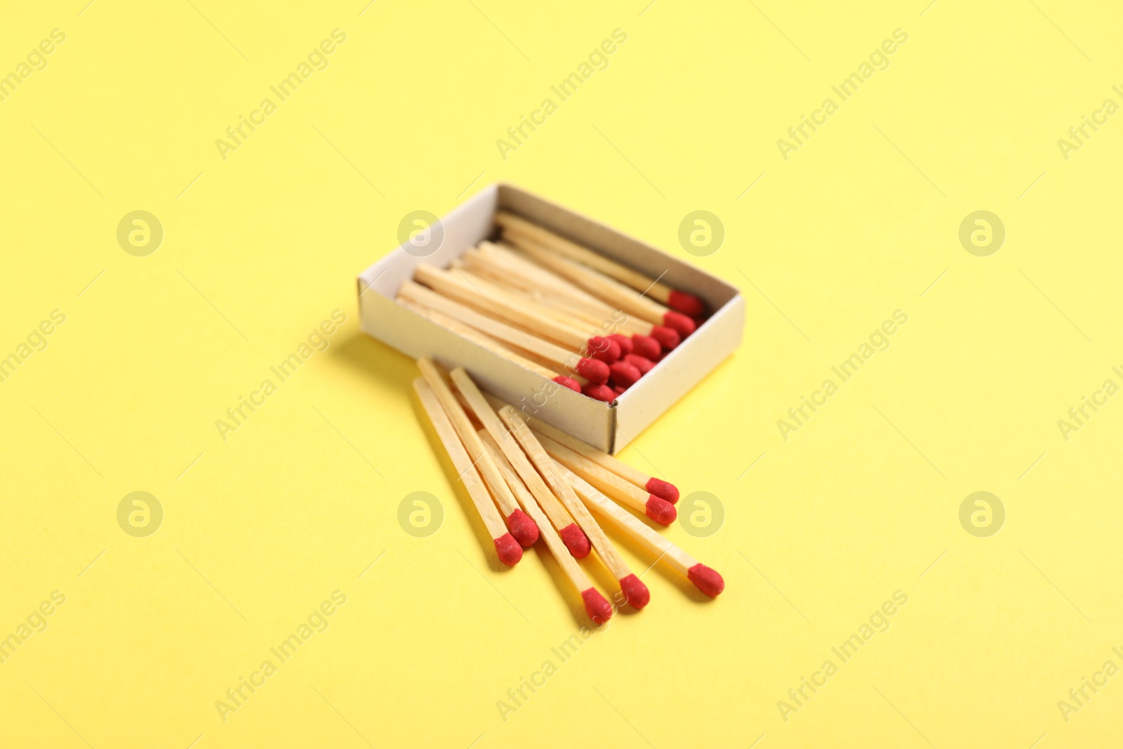 Matches and open box on yellow background Photo of Matches and open box on yellow background