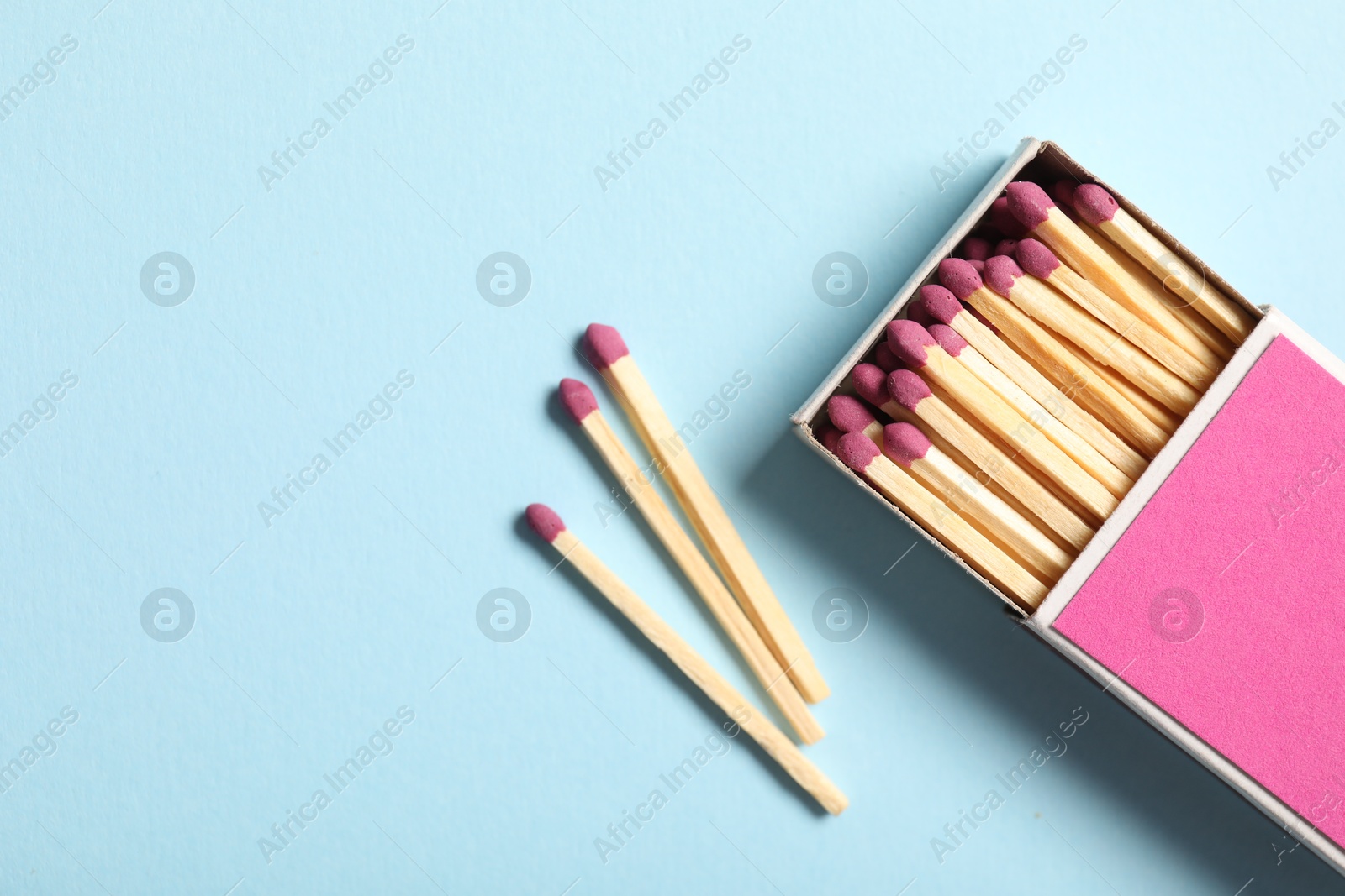 Photo of Matches and box on light blue background, flat lay. Space for text