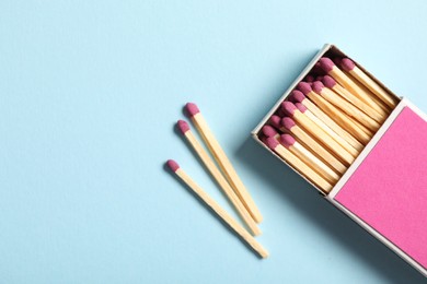 Photo of Matches and box on light blue background, flat lay. Space for text