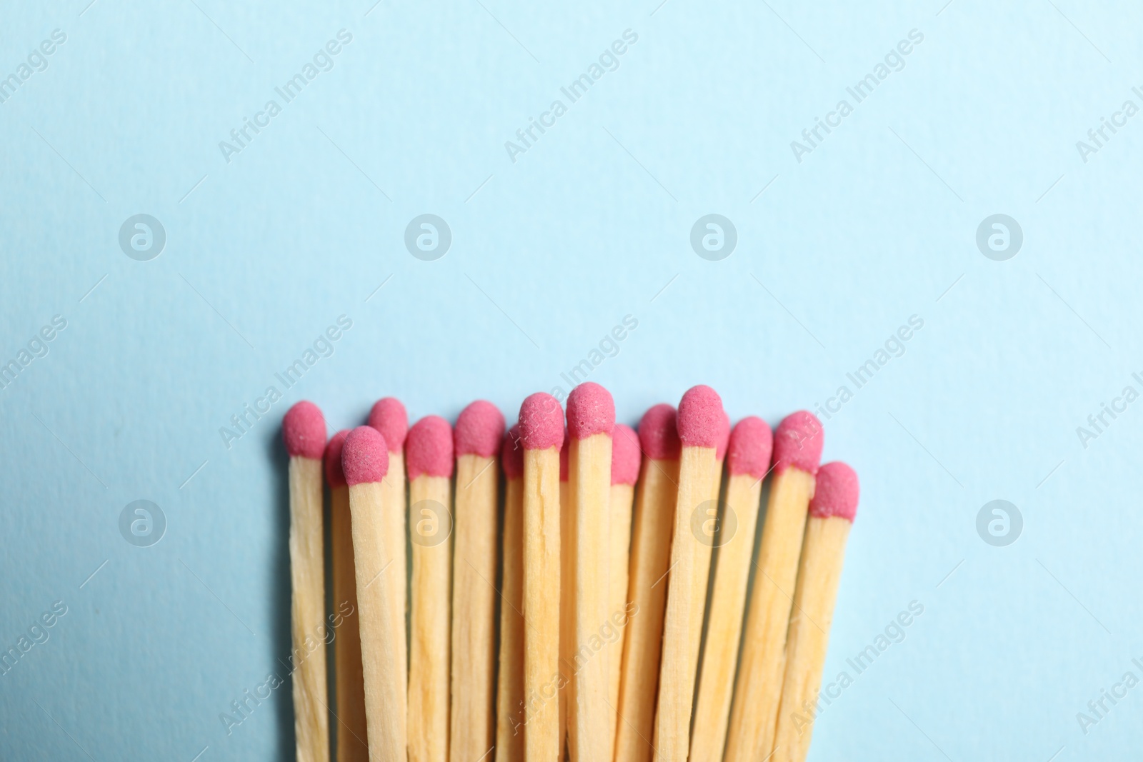 Photo of Matches with pink heads on light blue background, top view. Space for text