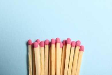 Photo of Matches with pink heads on light blue background, top view. Space for text