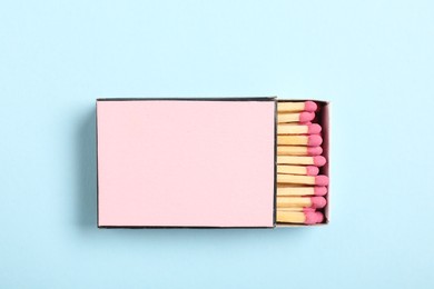 Photo of Matches in box on light blue background, top view. Mockup for design