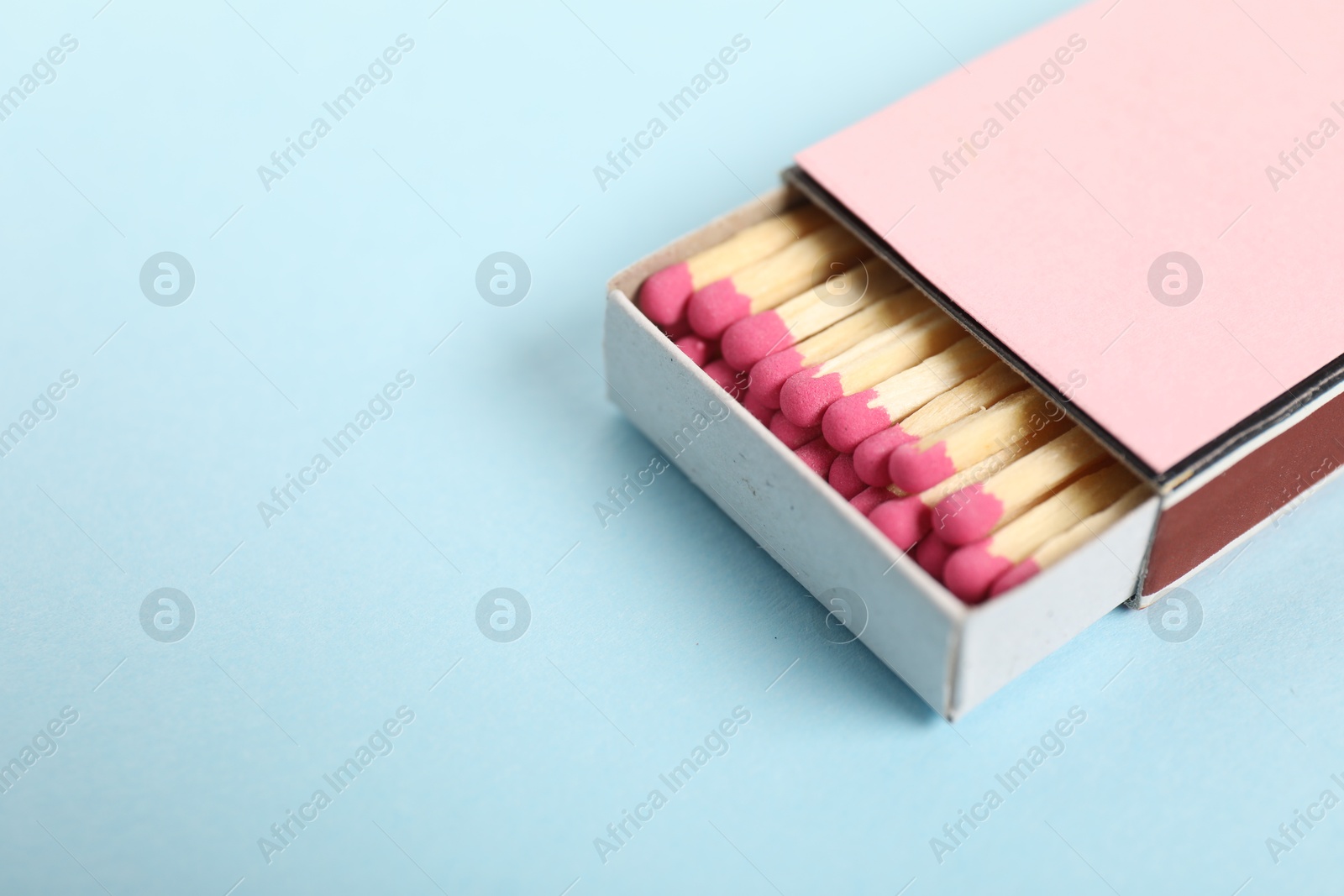 Matches in box on light blue background, closeup. Space for text Photo of Matches in box on light blue background, closeup. Space for text