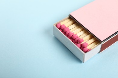 Photo of Matches in box on light blue background, closeup. Space for text