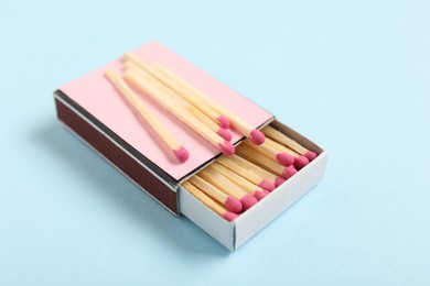 Photo of Matches in box on light blue background, closeup