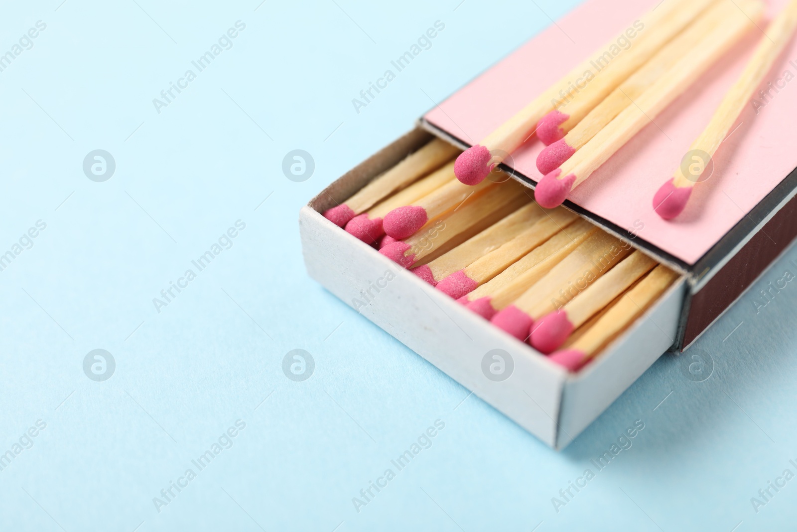 Matches and box on light blue background, closeup. Space for text Photo of Matches and box on light blue background, closeup. Space for text