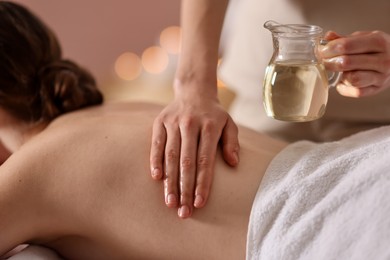 Photo of Woman receiving back massage with oil in spa salon, closeup
