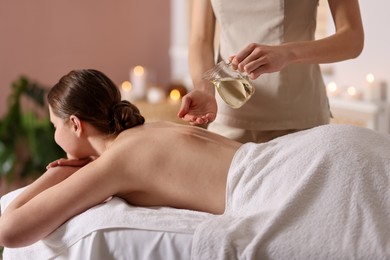Photo of Woman receiving back massage with oil in spa salon