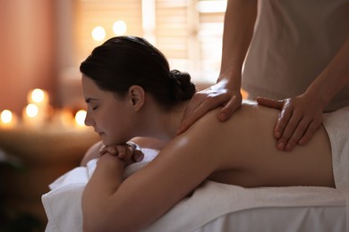 Photo of Woman receiving back massage with oil in spa salon