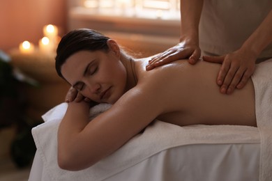 Photo of Woman receiving back massage with oil in spa salon