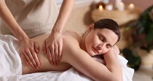 Photo of Woman receiving back massage with oil in spa salon