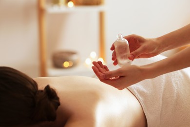 Photo of Woman receiving back massage with oil in spa salon, closeup