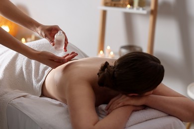 Photo of Woman receiving back massage with oil in spa salon