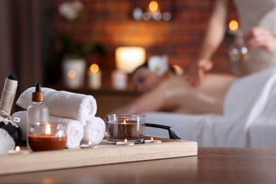 Photo of Woman receiving back massage with oil indoors, focus on different spa supplies