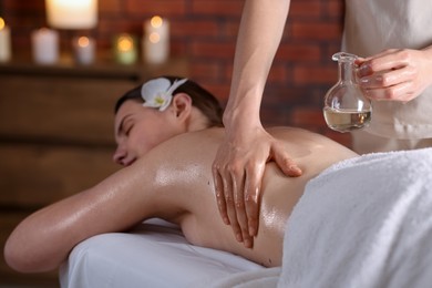 Photo of Woman receiving back massage with oil in spa salon