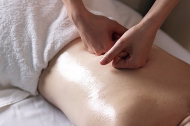 Photo of Woman receiving back massage with oil in spa salon, closeup