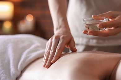 Photo of Woman receiving back massage with oil in spa salon, closeup