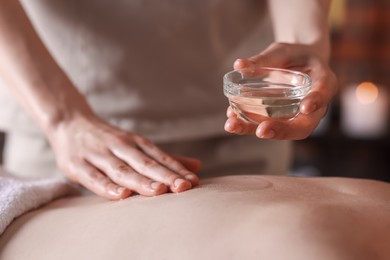 Photo of Woman receiving back massage with oil in spa salon, closeup