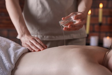 Photo of Woman receiving back massage with oil in spa salon, closeup