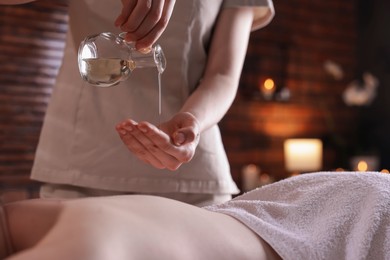 Photo of Woman receiving back massage with oil in spa salon, closeup