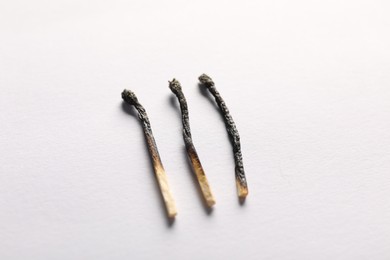 Photo of Burnt matches on light grey background, closeup view