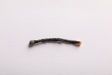 Photo of One burnt match on light grey background, top view