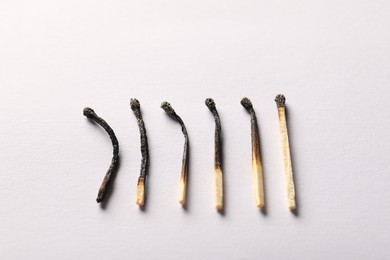Photo of Burnt matches on light grey background, closeup