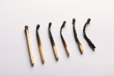 Photo of Burnt matches on light grey background, closeup