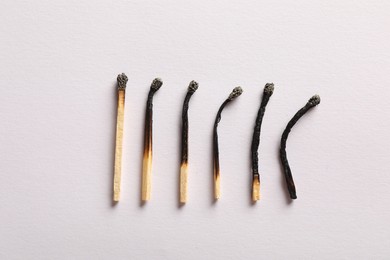 Photo of Burnt matches on light grey background, flat lay