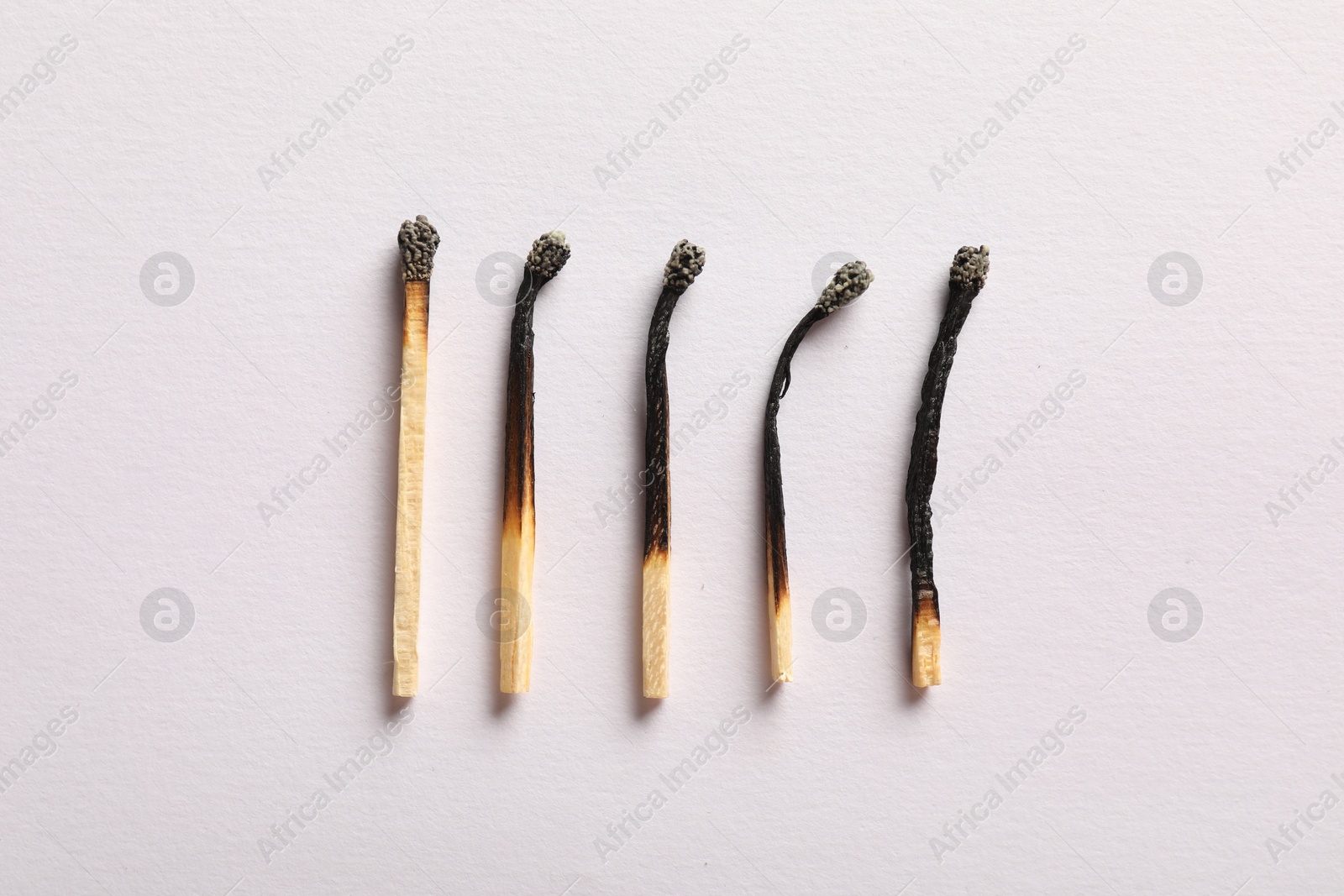 Burnt matches on light grey background, flat lay Photo of Burnt matches on light grey background, flat lay