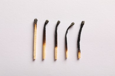Photo of Burnt matches on light grey background, flat lay