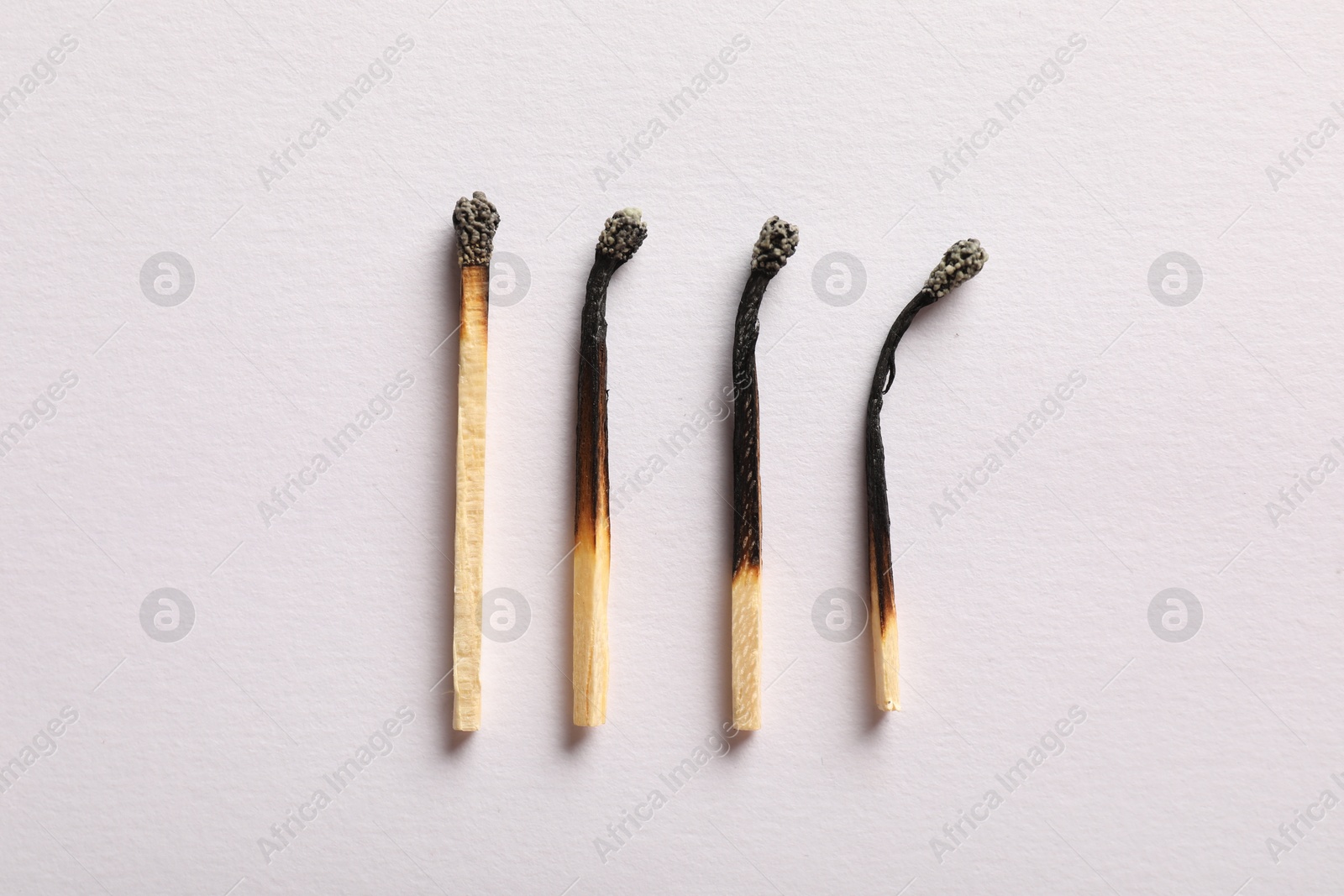 Burnt matches on light grey background, flat lay Photo of Burnt matches on light grey background, flat lay