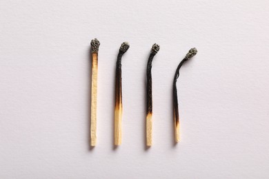 Photo of Burnt matches on light grey background, flat lay