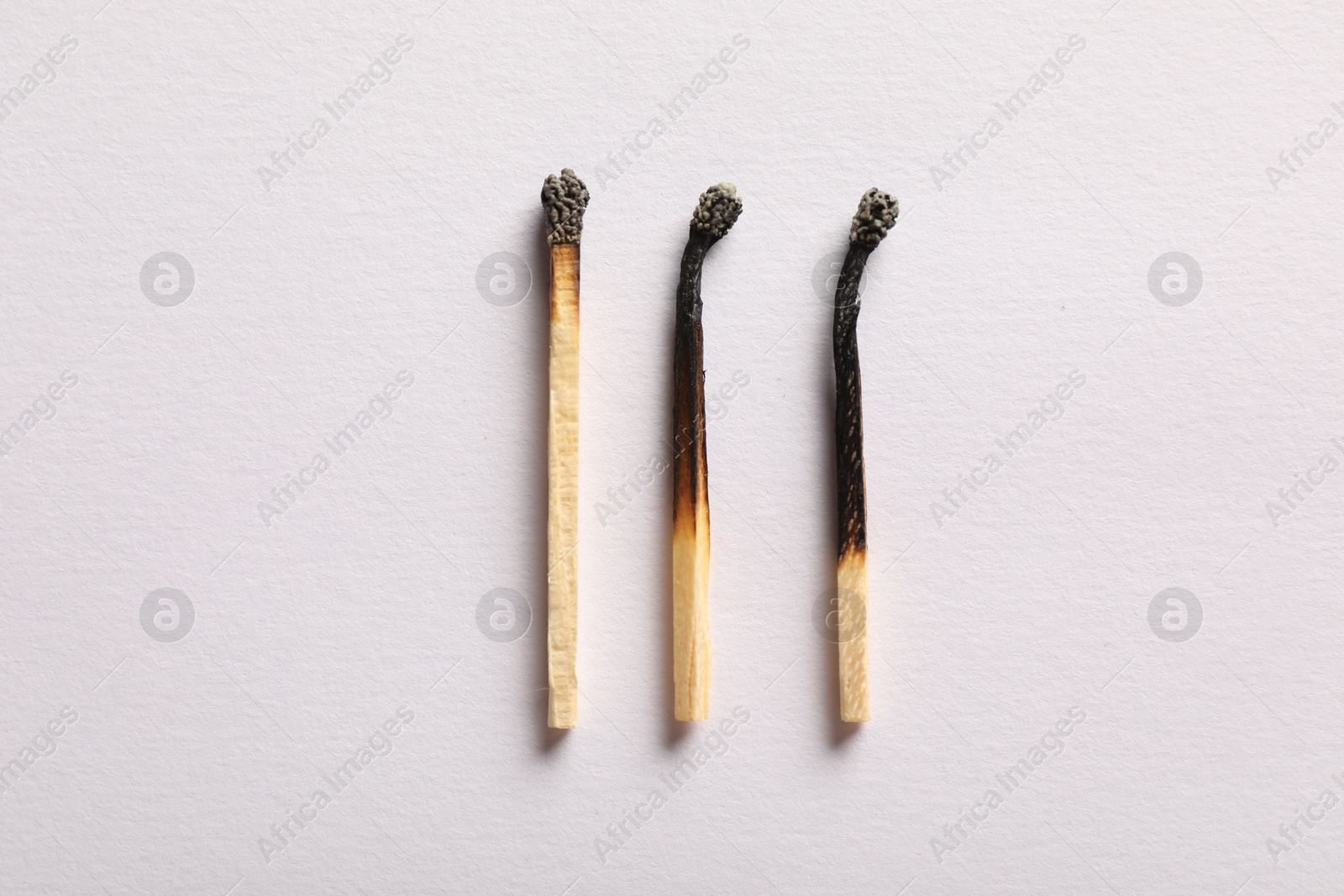 Burnt matches on light grey background, flat lay Photo of Burnt matches on light grey background, flat lay