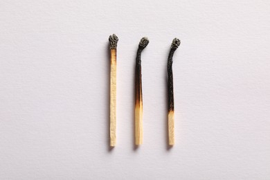Photo of Burnt matches on light grey background, flat lay