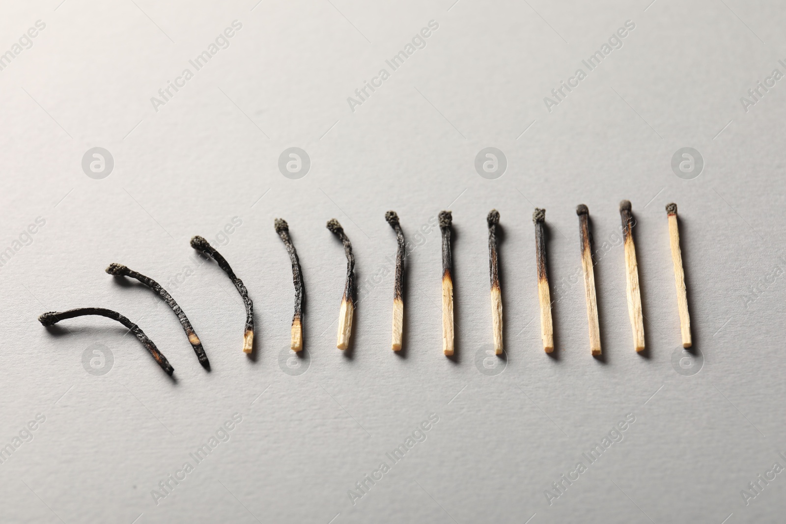 Photo of Burnt matches on grey background, above view