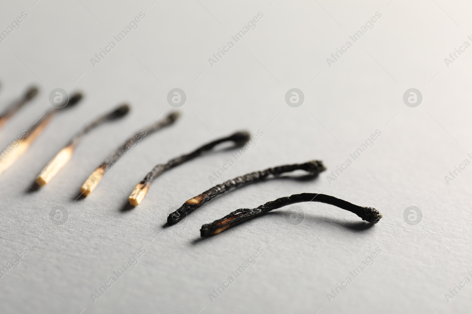 Burnt matches on grey background, closeup view Photo of Burnt matches on grey background, closeup view