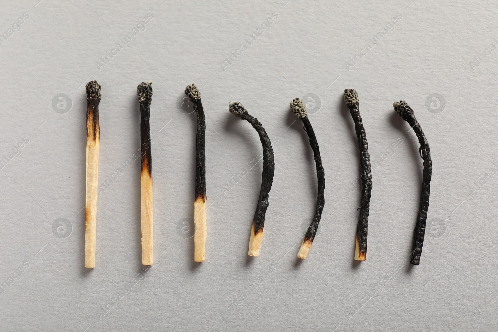 Burnt matches on grey background, flat lay Photo of Burnt matches on grey background, flat lay
