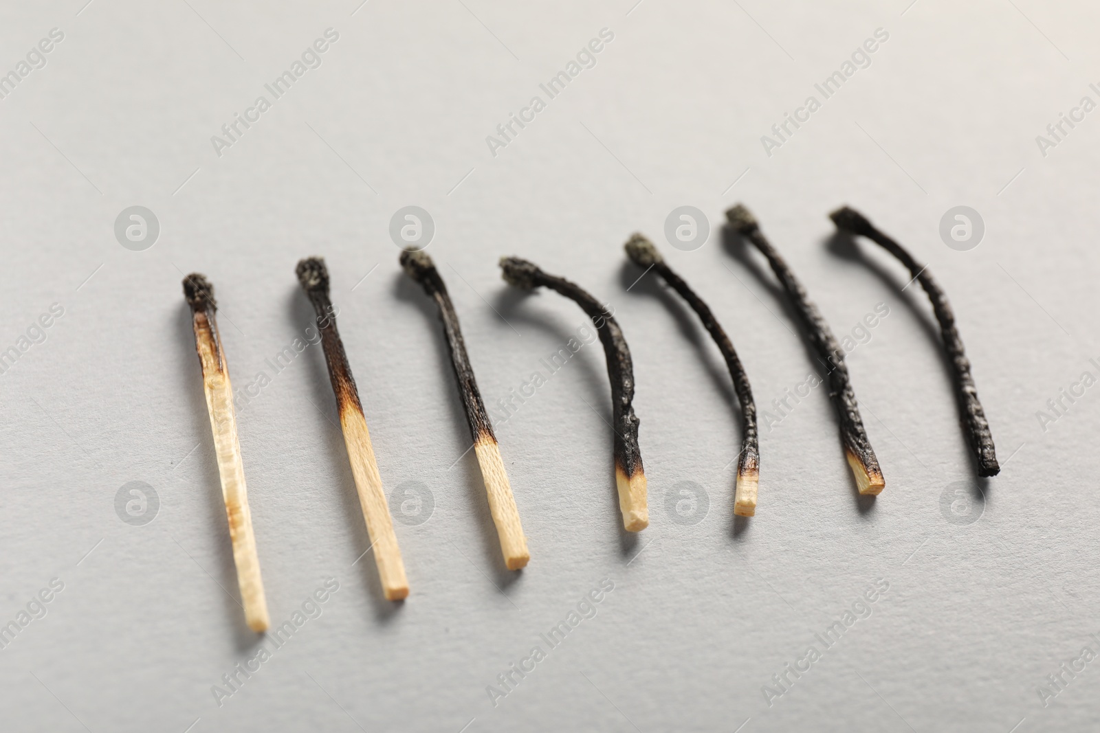Burnt matches on grey background, closeup view Photo of Burnt matches on grey background, closeup view