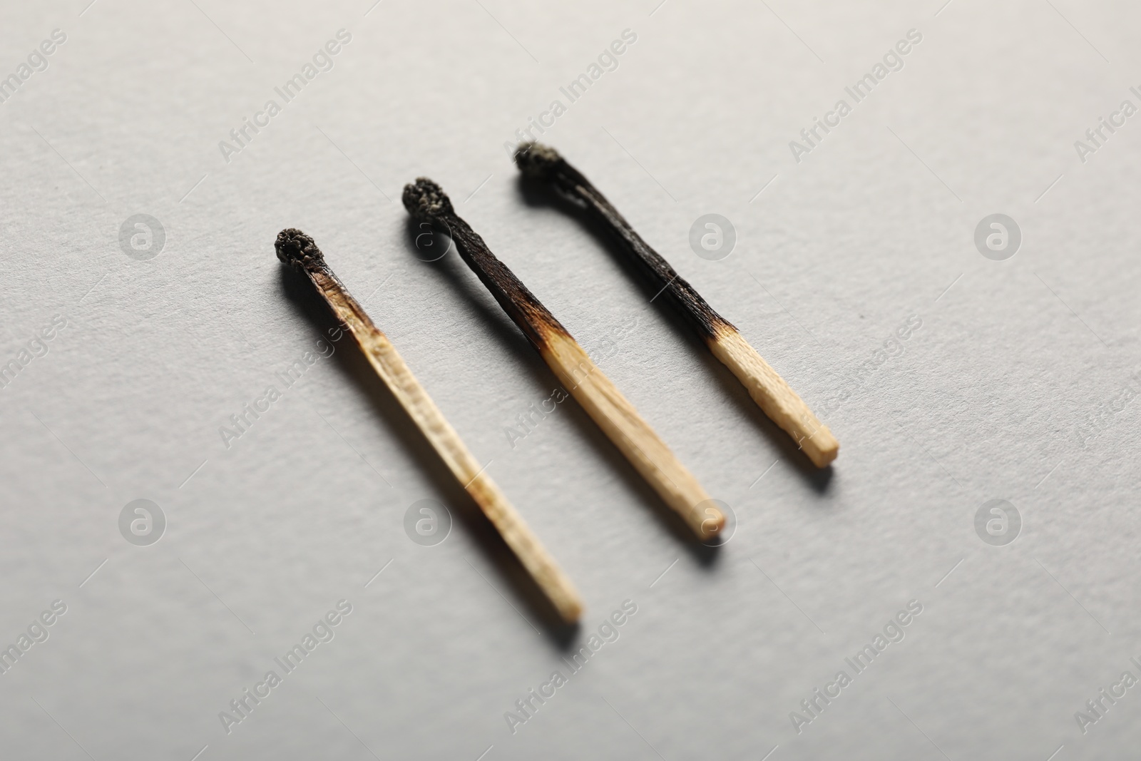 Burnt matches on grey background, closeup view Photo of Burnt matches on grey background, closeup view