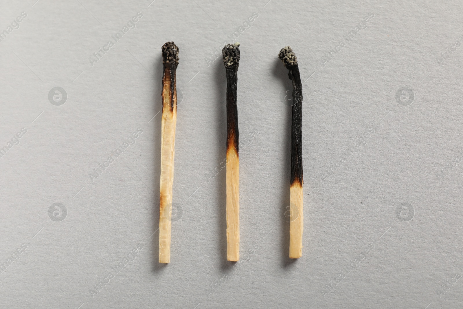 Burnt matches on grey background, flat lay Photo of Burnt matches on grey background, flat lay
