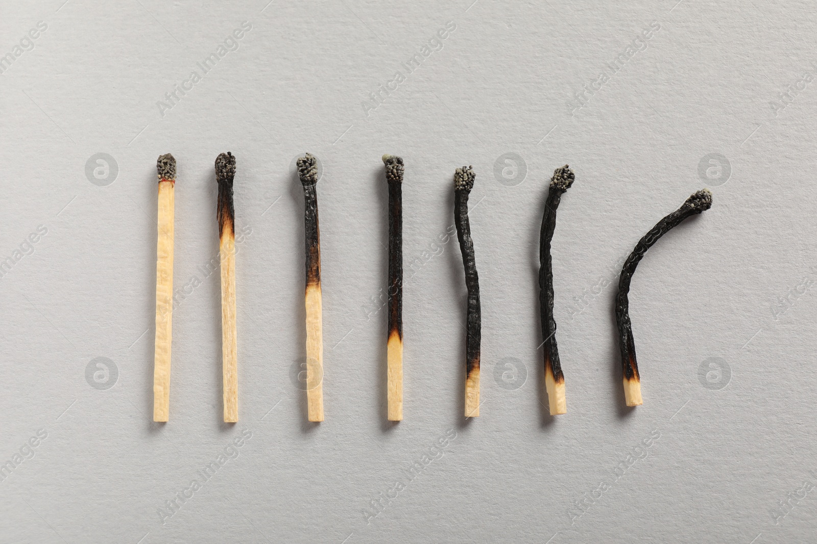 Burnt matches on grey background, flat lay Photo of Burnt matches on grey background, flat lay