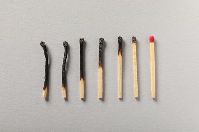 Photo of Burnt and whole matches on grey background, flat lay