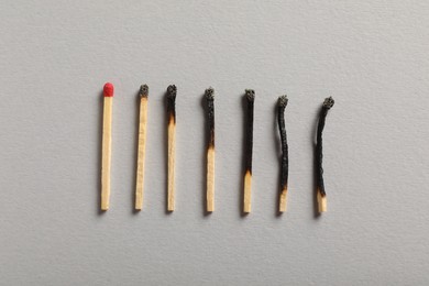 Photo of Burnt and whole matches on grey background, flat lay