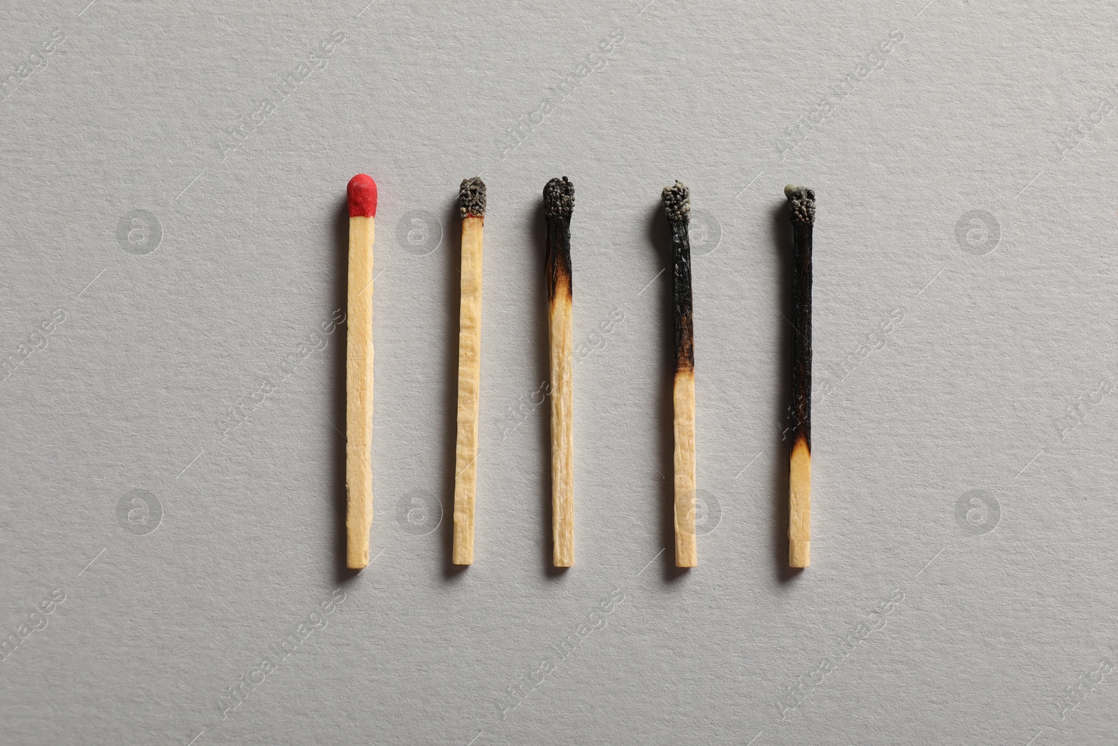 Burnt and whole matches on grey background, flat lay Photo of Burnt and whole matches on grey background, flat lay