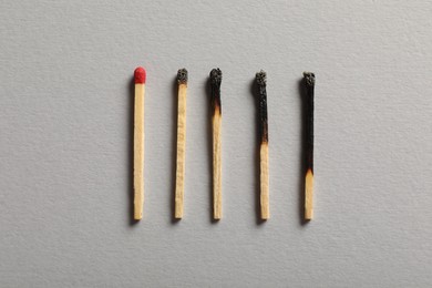 Photo of Burnt and whole matches on grey background, flat lay